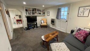 A living room with a sofa, coffee table, TV stand, and bookshelf. - Private Apartment on Beautiful Grounds, Walking Distance to Landrum SC (Landrum)
