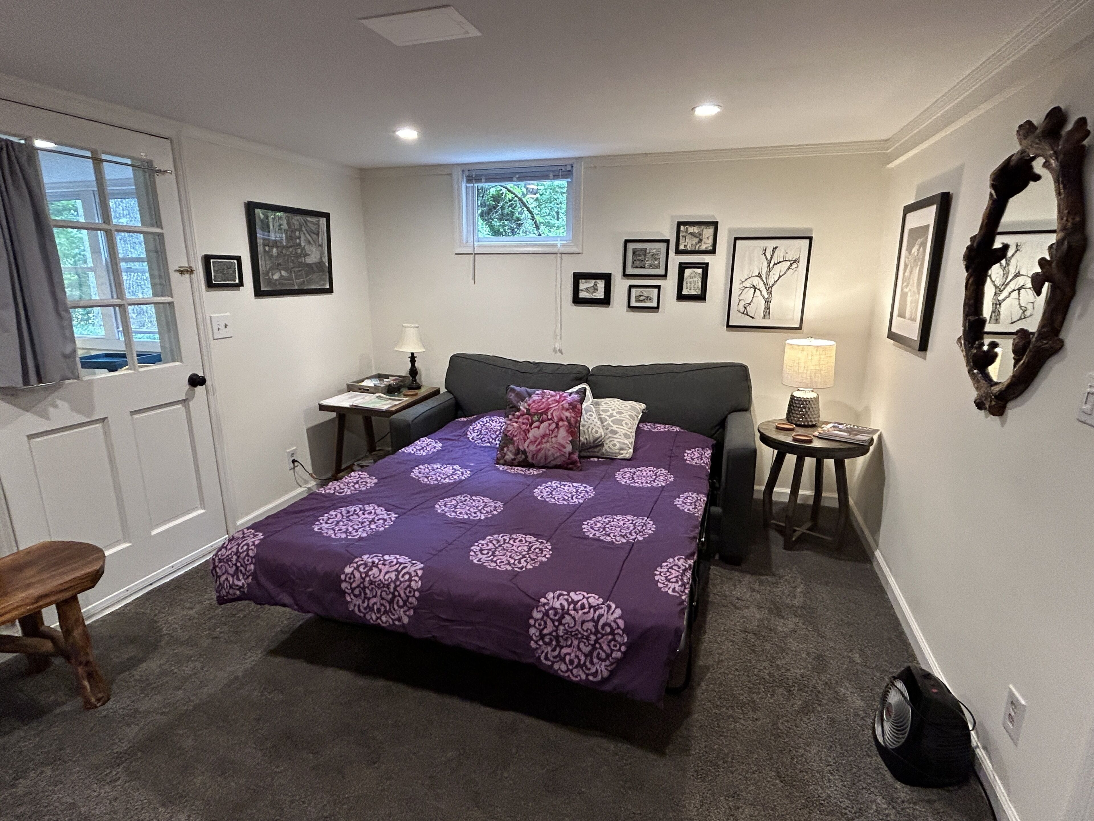 Un dormitorio con cama, mesitas de noche, una ventana y adornos en la pared.