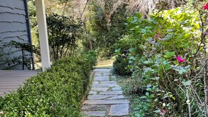 A stone pathway leading to a house with a covered porch. - Private Apartment on Beautiful Grounds, Walking Distance to Landrum SC (Landrum)