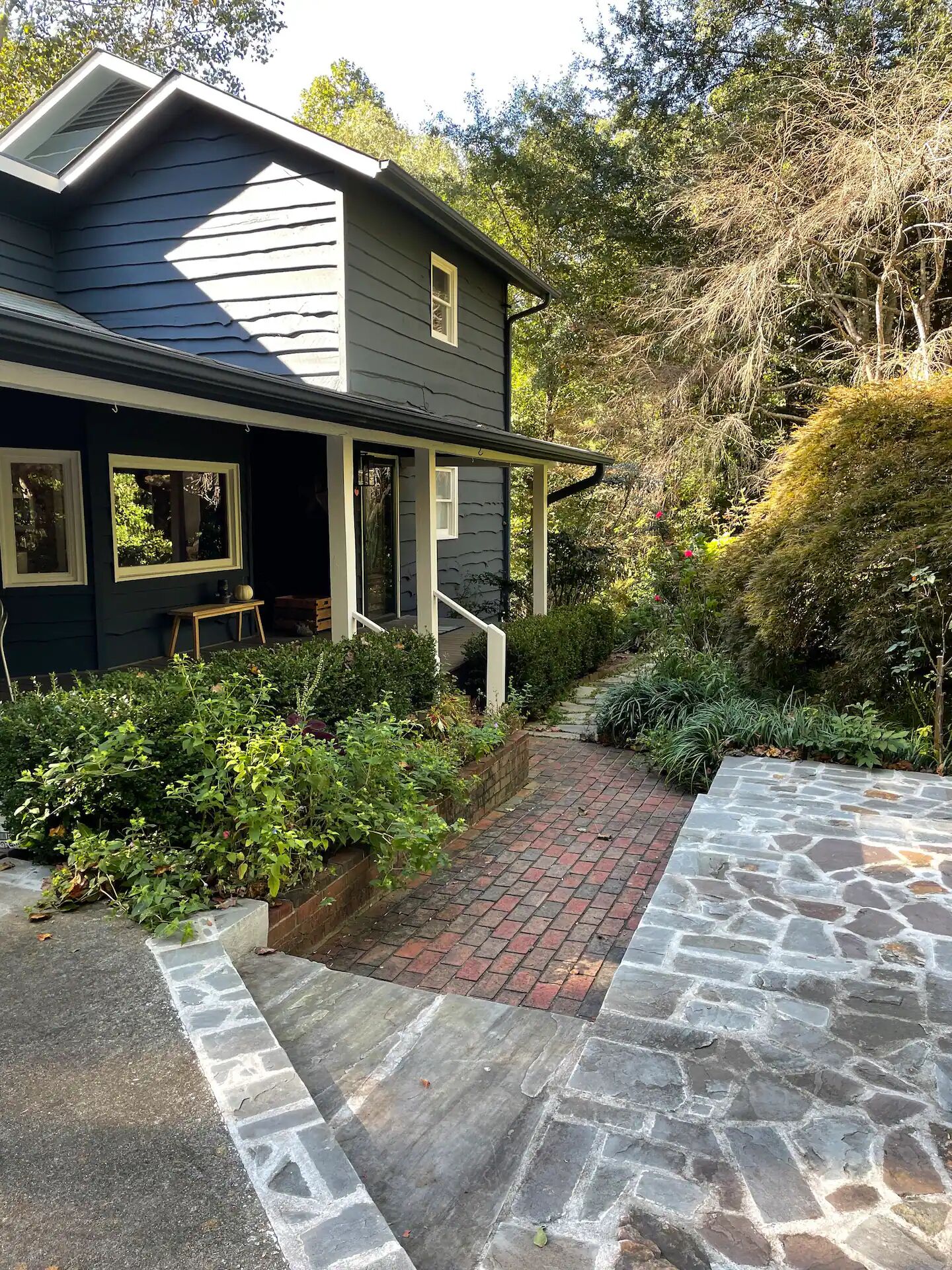A house with a stone pathway leading to the front door, surrounded by greenery and a brick border.