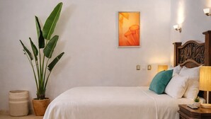 A bedroom with a bed, a potted plant, a wall-mounted air conditioner, a framed picture, and a bedside table with a lamp. - New listing, Open air apartment,  pool, balcony & jungle view. 5 mins to beach (Sayulita)