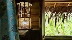 Una habitación con una lámpara de fibra y vista a palmeras a través de una ventana.