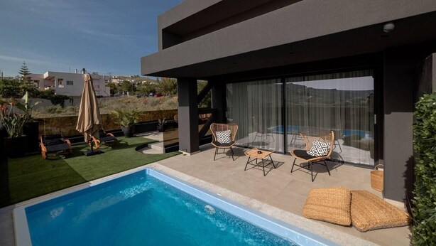 A modern outdoor pool area with a clear blue pool, lounge chairs, and a covered seating area. - Inviting 4-Bed Villa Lia in Vathianos Kampos (Vathianos Kampos)