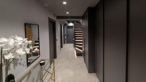 A modern hallway with a light-colored floor, dark walls, and a staircase with illuminated steps. - Beautiful 4-Bed Villa Ria in Vathianos Kampos (Vathianos Kampos)
