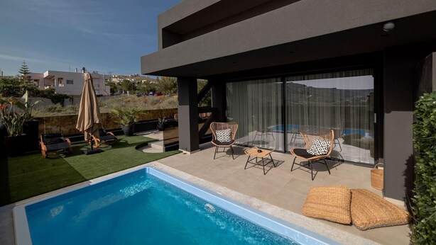 A modern outdoor pool area with a clear view of the pool, lounge chairs, and a covered seating area. - Beautiful 4-Bed Villa Ria in Vathianos Kampos (Vathianos Kampos)