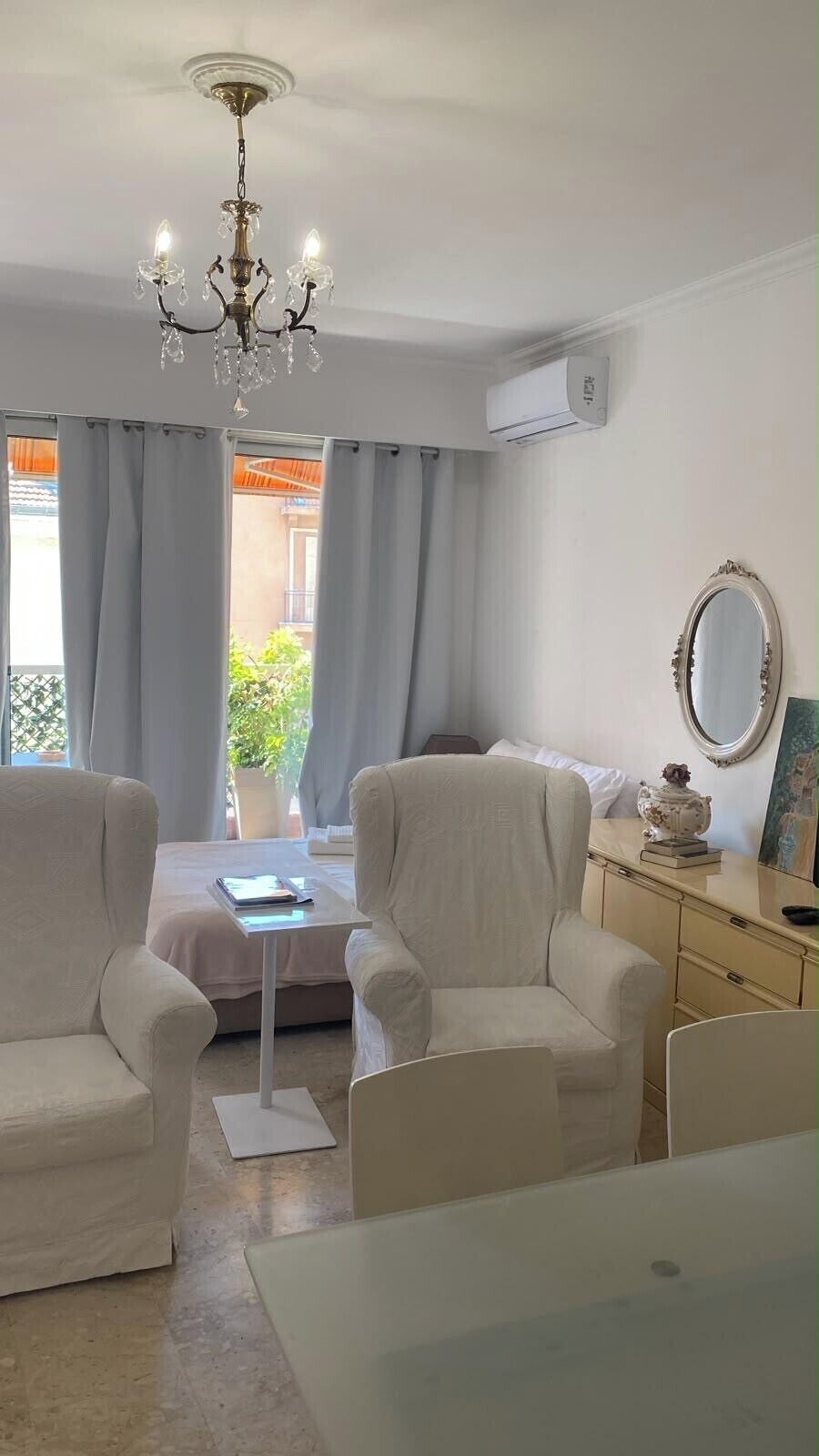 A modern living room with a chandelier, a sofa, a coffee table, and a dresser with a mirror.