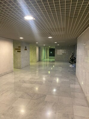 A corridor with a tiled floor, a grid ceiling with recessed lighting, and directional signs on the walls. - Studio 907 Sleeps 4 Near Casino (Monte Carlo)