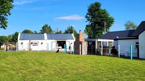 A fenced property with a white building, a brick structure, and a covered area. - Stunning 1-Bed Barn in Ballintubber (Ballintubber)