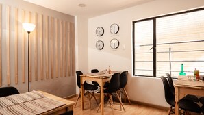A dining area with a wooden table and chairs, a lamp, and clocks on the wall. - Primitivo Usaquén dn (Bogotá)