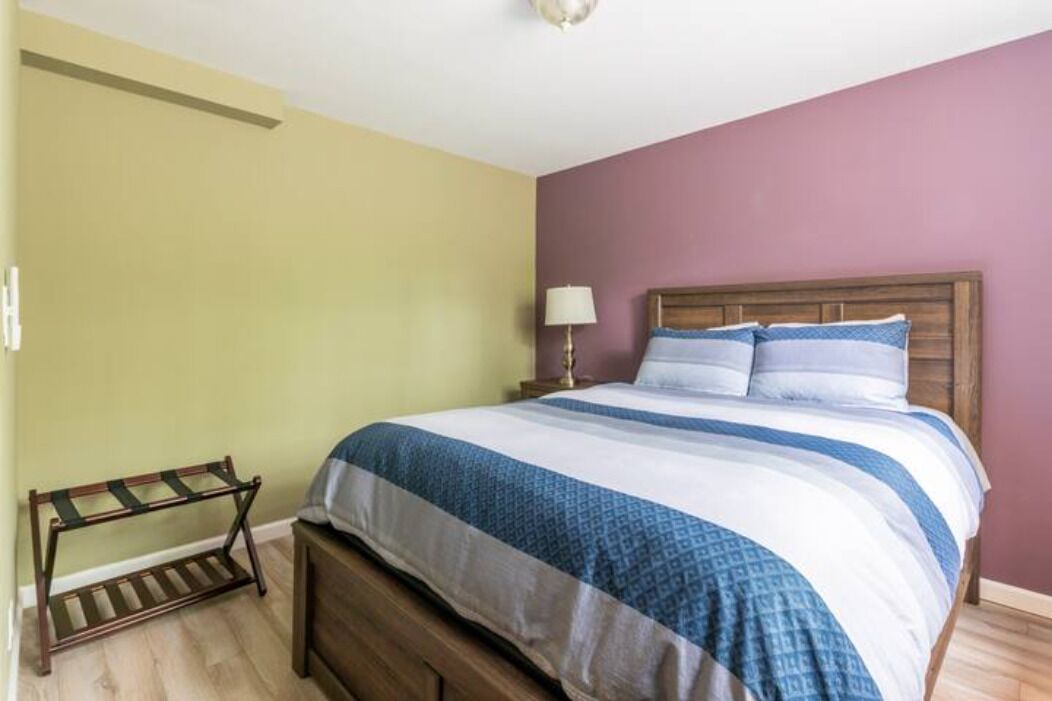 Une chambre avec un lit en bois, une table de chevet avec une lampe et un banc en bois.