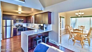 A modern kitchen with stainless steel appliances, a central island, and wooden cabinets.