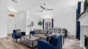 A modern living room with a sofa, armchairs, a coffee table, and a dining area with a table and chairs. - Hidden Gem in Fort Worth with Hot Tub & Mini Golf (Watauga)