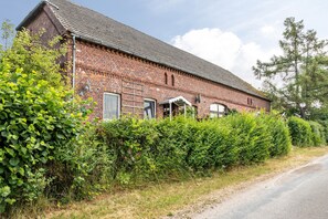 A brick building with a sloped roof, a door, and a window.