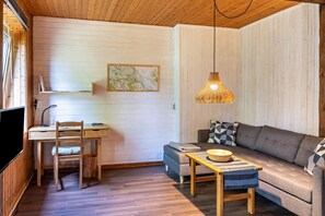 A room with a wooden desk, a sofa, a hanging lamp, and a map on the wall.