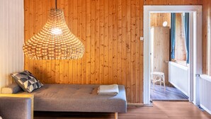 Une pièce avec un canapé, un luminaire suspendu et un mur en bois.