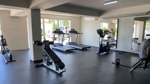 Une salle de sport équipée de tapis de course, d’un banc de développé couché et d’un kettlebell.