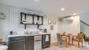 Cozinha moderna com forno embutido, cafeteira e pequena área de refeições com duas cadeiras e uma mesa.