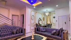 Un salon luxueux, agrémenté de deux canapés richement décorés, d’une table basse centrale et d’un lustre.