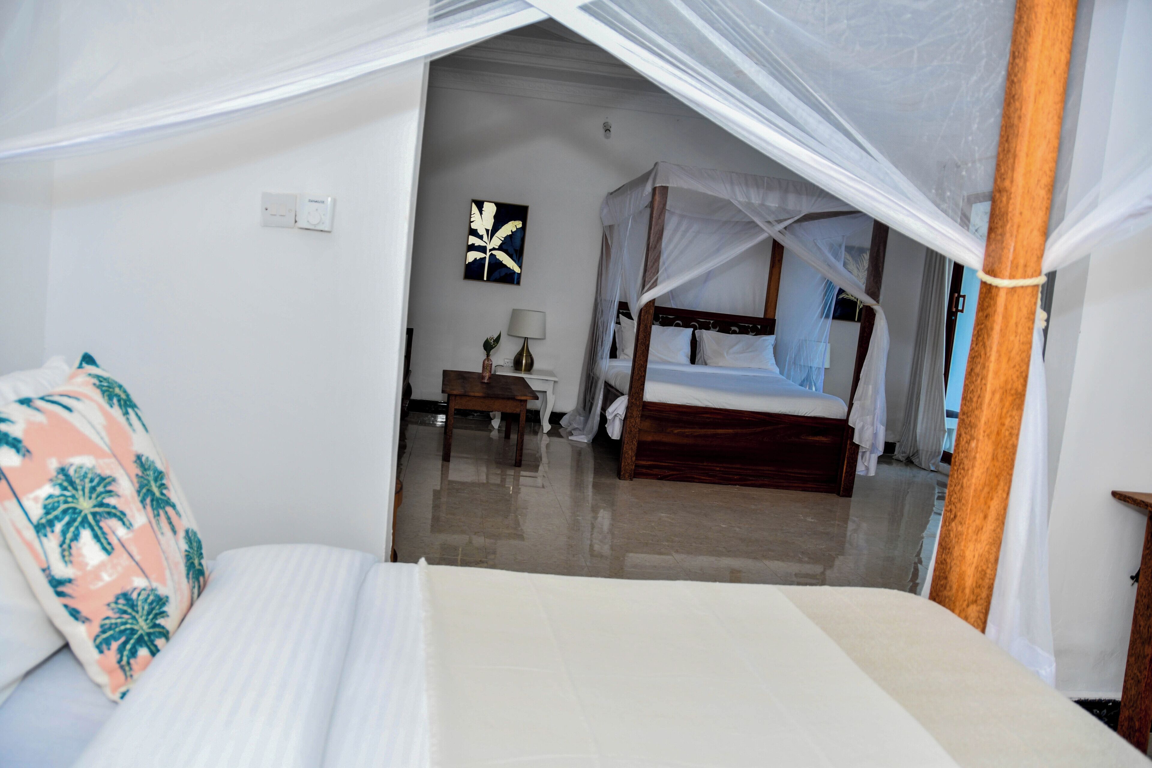 A bedroom with a bed, a bedside table, a nightstand, a lamp, and a wall-mounted artwork.