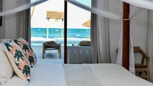 A bedroom with a bed, a view of the beach, and a chair. - Coral Bay Zanzibar (Pongwe)