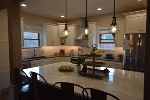 A modern kitchen with white cabinets, a central island, and pendant lighting.