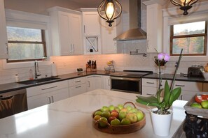 A kitchen with white cabinets, a marble island, and a potted plant. - Mustard Seed Farm Estate in Saluda, NC! (Saluda)