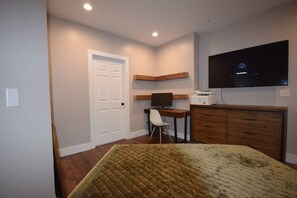 A bedroom with a bed, a desk with a computer, a television, and a wardrobe.