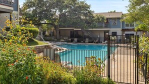 A residential building with a swimming pool, surrounded by a fence and various plants. - SoCo Condo, 2br/2ba, updated bright space with great pool + parking! (Austin)