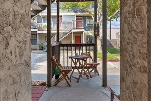 A covered outdoor seating area with a table and chairs, a fire extinguisher, and a view of a residential building in the background. - SoCo Condo, 2br/2ba, updated bright space with great pool + parking! (Austin)