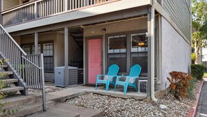 A two-story building with a porch, a pink door, and two blue chairs. - SoCo Condo, 2br/2ba, updated bright space with great pool + parking! (Austin)