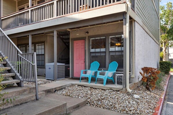 A two-story building with a porch, a pink door, and two blue chairs. - SoCo Condo, 2br/2ba, updated bright space with great pool + parking! (Austin)