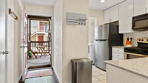 A modern kitchen with stainless steel appliances, a trash bin, and a small island. - SoCo Condo, 2br/2ba, updated bright space with great pool + parking! (Austin)