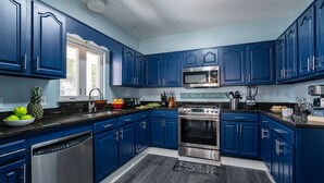 Een moderne keuken met blauwe kastjes, roestvrijstalen apparatuur en een granieten aanrecht.