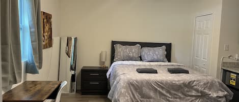 A bedroom with a bed, bedside tables, a desk, and a ceiling fan.