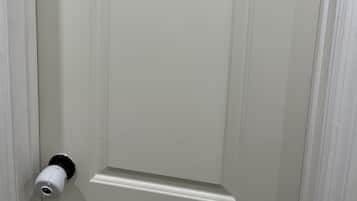 Una puerta cerrada con un picaporte blanco y un mirallobrecha.