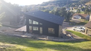 A modern two-story house with a flat roof, large windows, and a driveway with a parked truck.