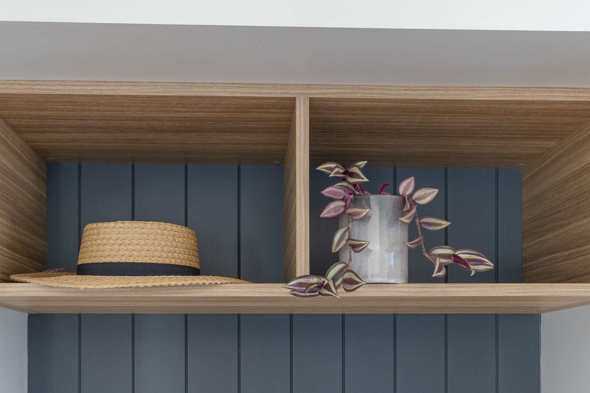 Une étagère avec un panier en osier et un vase contenant une plante.