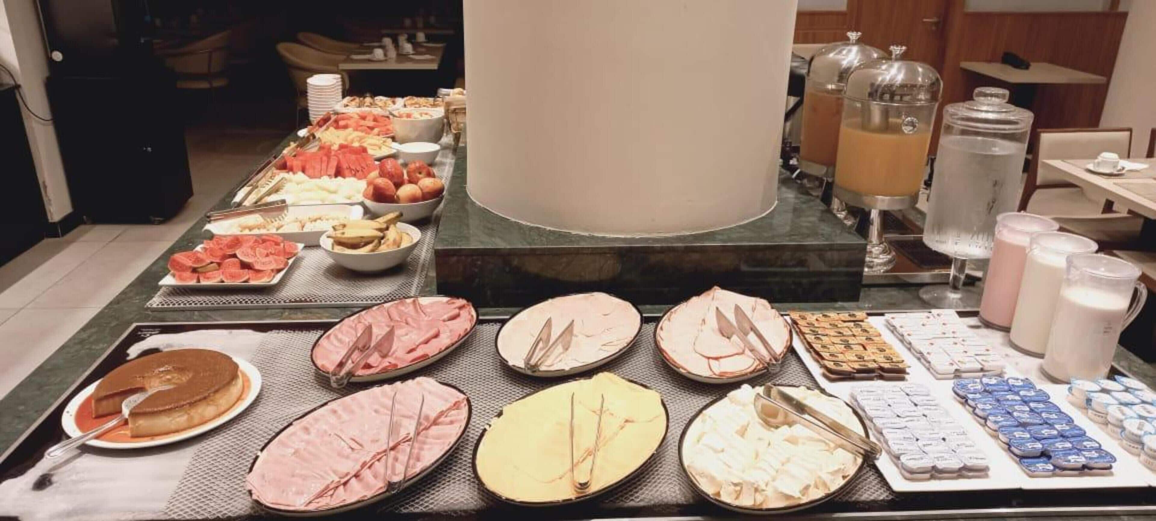 Ein Buffet mit verschiedenen Speisen, darunter Obst, Fleisch und Gebäck.