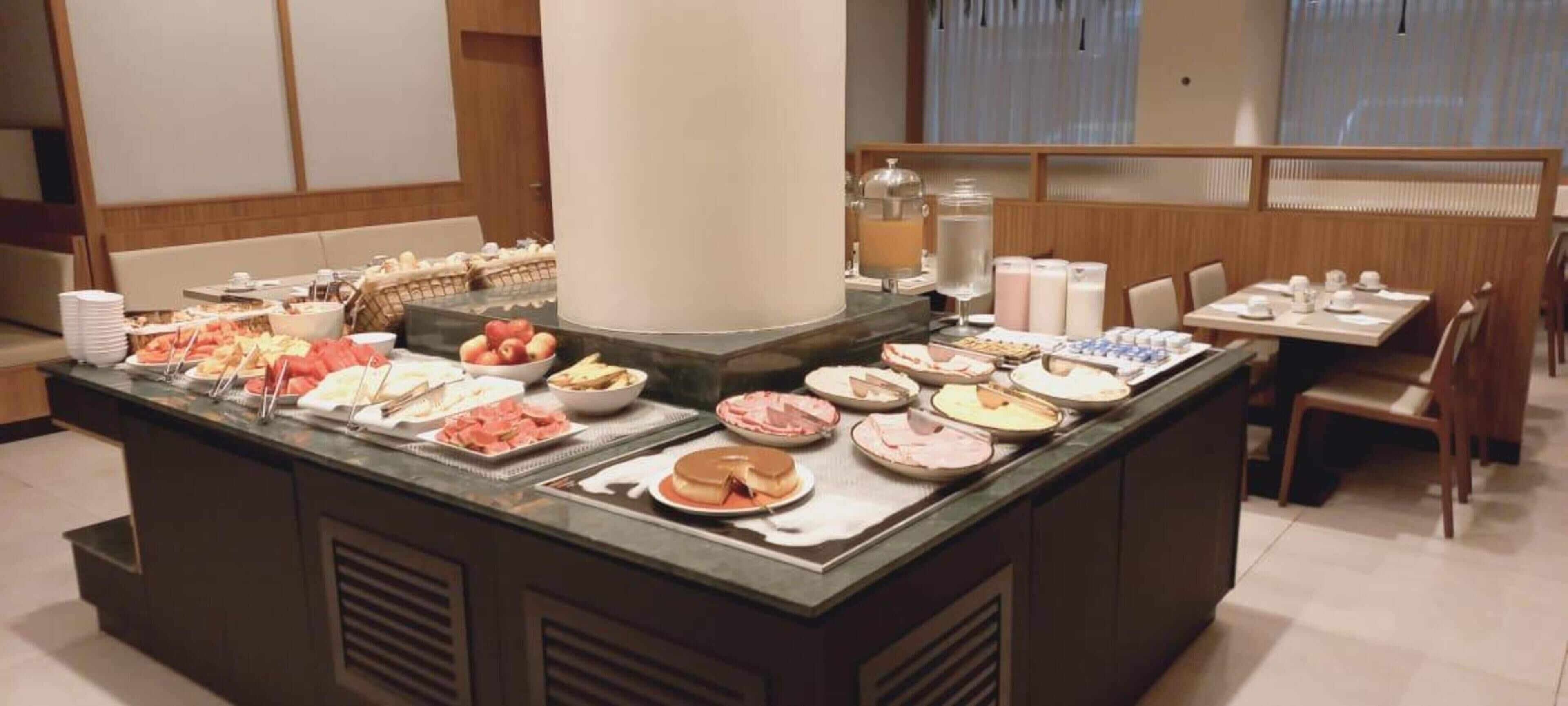 A buffet area with various food items and a seating area with tables and chairs.