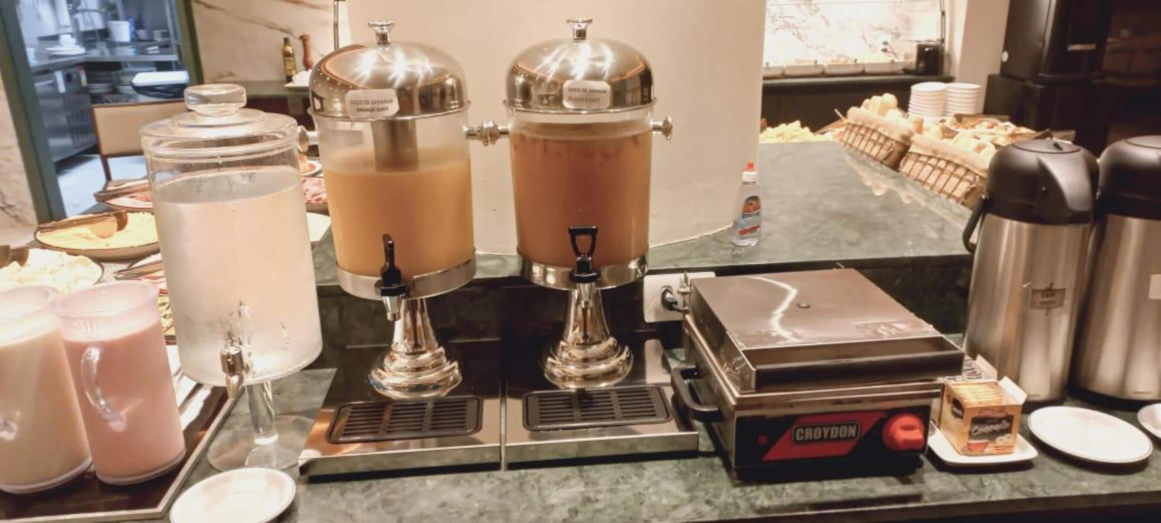 A coffee station with two coffee dispensers, a coffee maker, and a box of creamer.