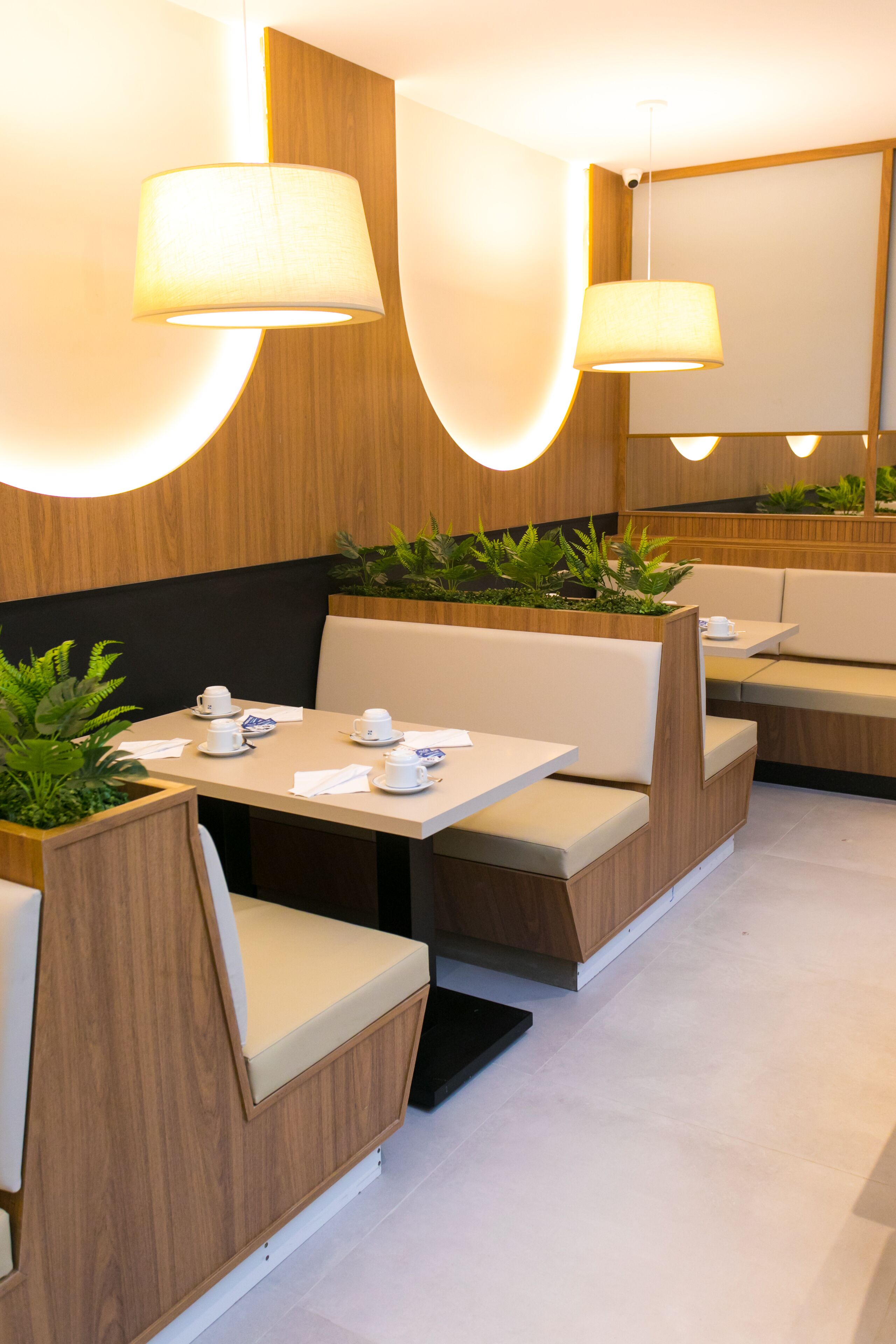 Un restaurante moderno con paneles de madera, asientos acolchados y lámparas colgantes.