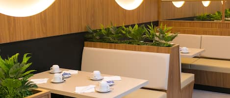Un restaurante moderno con paneles de madera, asientos acolchados y lámparas colgantes.