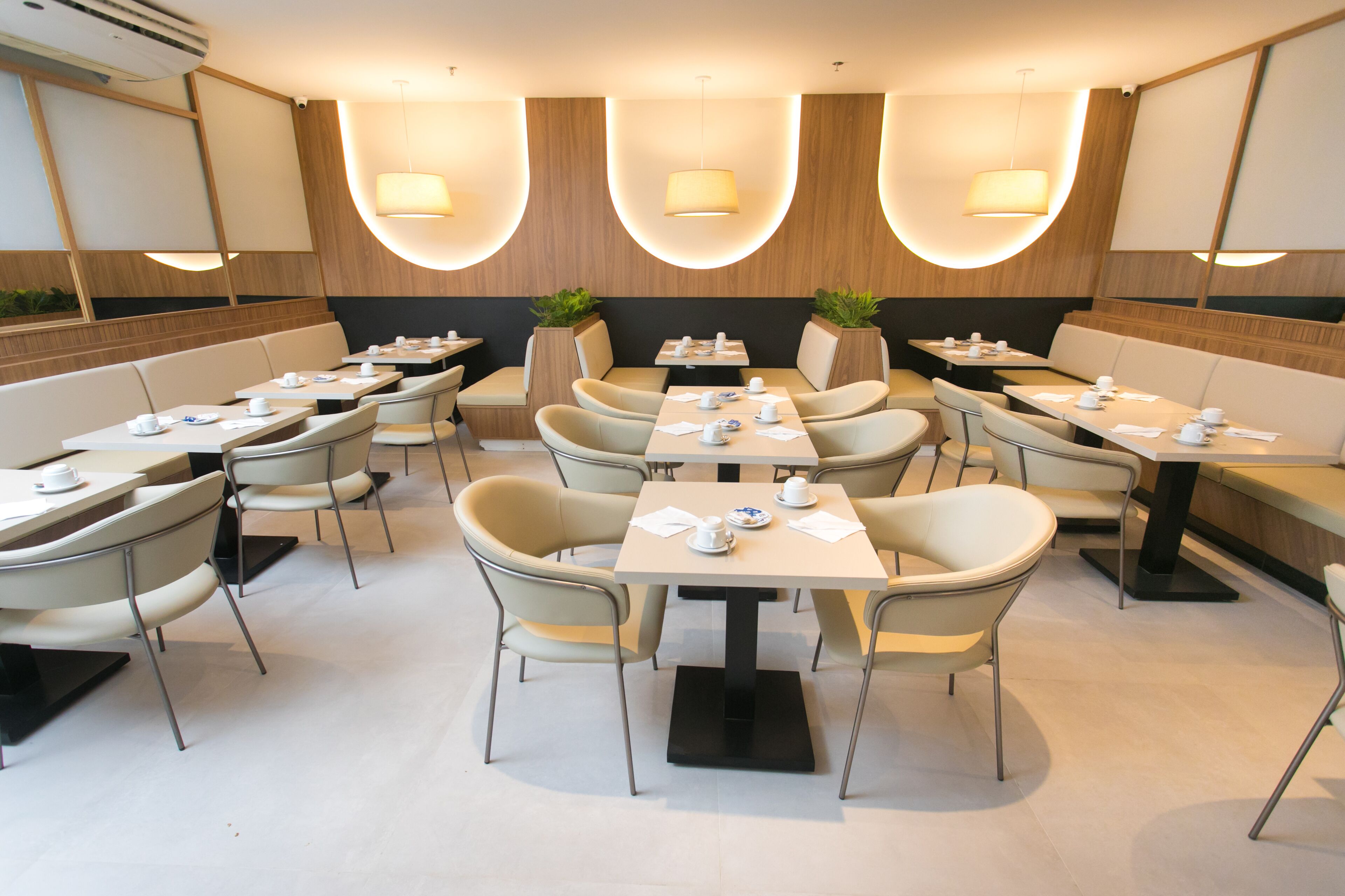 Een modern restaurant met zowel zitjes als tafels, elk voorzien van borden, bekers en bestek.