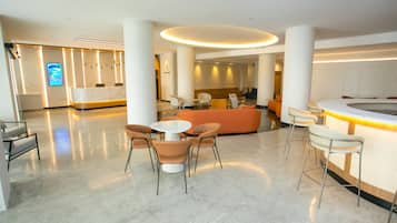 Un moderno vestíbulo de hotel con mostrador de recepción, zona de estar y una gran pantalla digital.