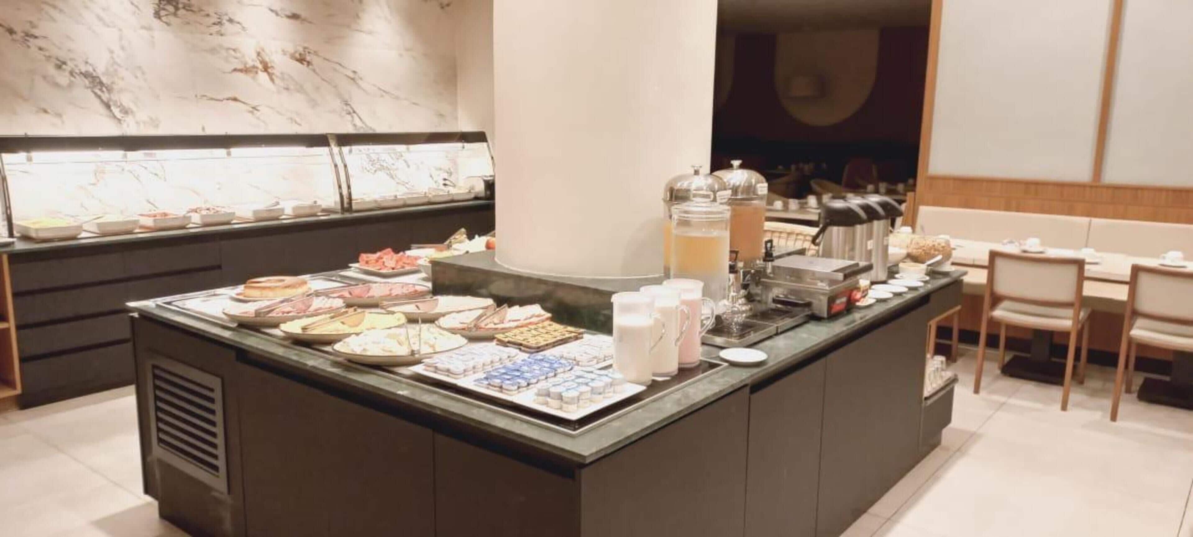 A buffet counter with various food items and beverages.