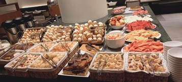 Buffet com diversos alimentos, incluindo doces, frutas e legumes.