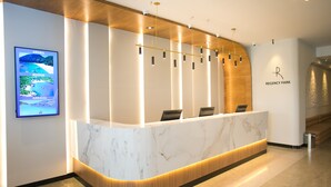 Una recepción con encimera de mármol, panel de madera y un letrero que dice 'REGENCY PARK'.
