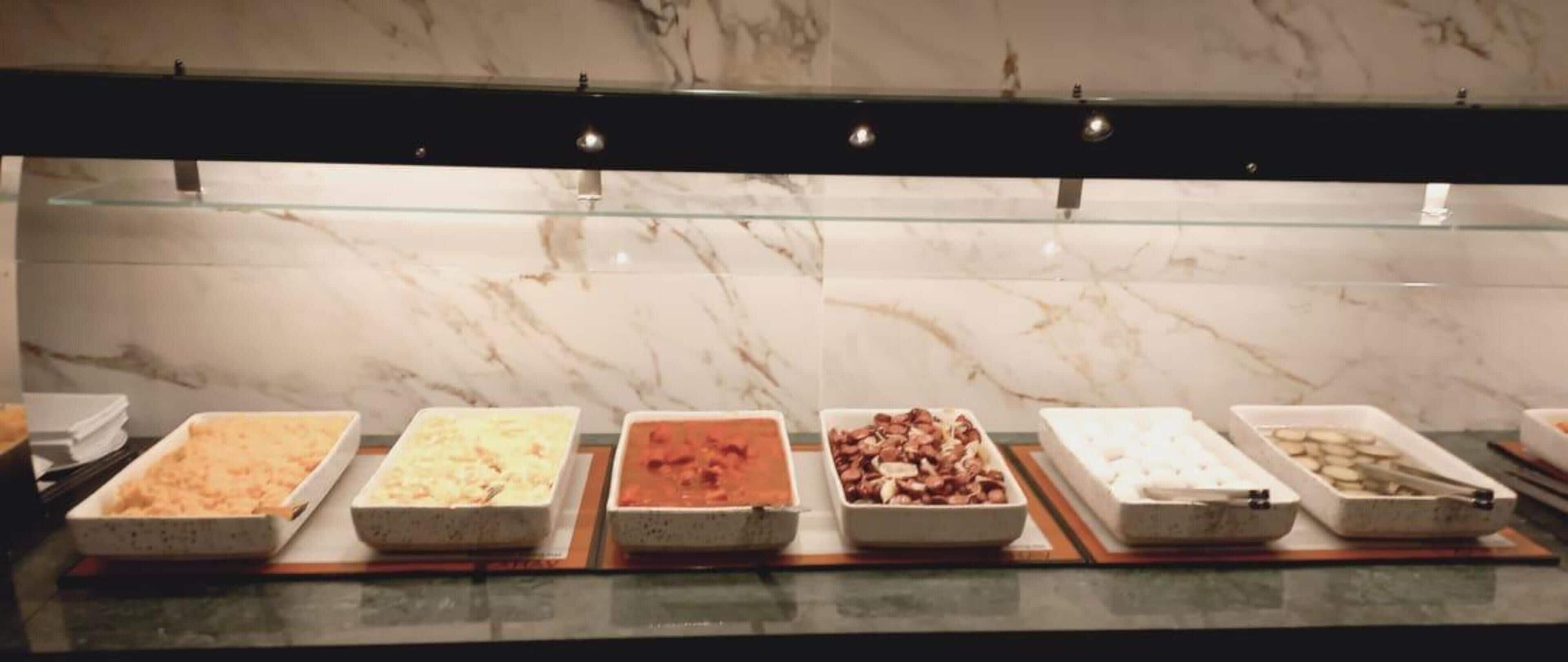 Un buffet proposant divers plats présentés dans des plateaux rectangulaires.
