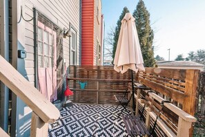 Una terraza de madera con piso estampado, una banca y un área cubierta con mesa y sillas.