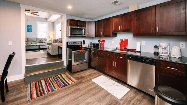 Una cocina moderna con armarios de madera oscura, electrodomésticos de acero inoxidable y un tapete colorido.